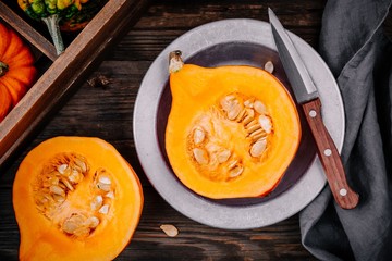 raw pumpkin slices with seeds on a wooden background.