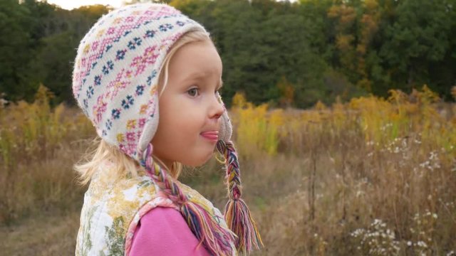 Little girl in the autumn forest. The child is somewhat agitated and worried and informs about this by turning to the camera.