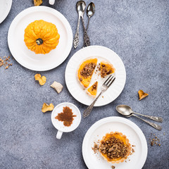 Thanksgiving day concept with homemade pumpkin tartlet, mini pie, on gray stone background. Healthy autumn food flat lay, copy space, top view.