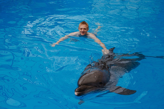 happy man swim with dolphin in dolphinarium