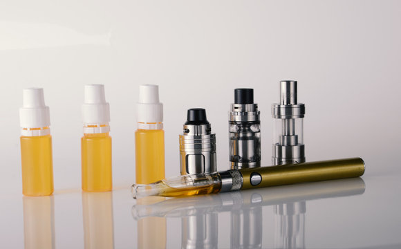 isolated vape tanks and e liquid for electronic cigarette or e cig over a white background. vaping rdta and e juice for vaping devices.