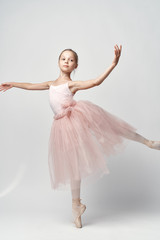 Naklejka premium A small ballerina in a light dress demonstrates her skills