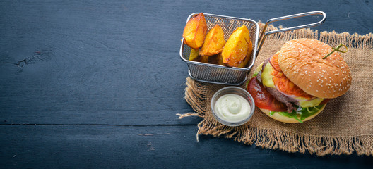 Burger and potatoes with sauce. On a wooden background. Top view. Free space for your text.