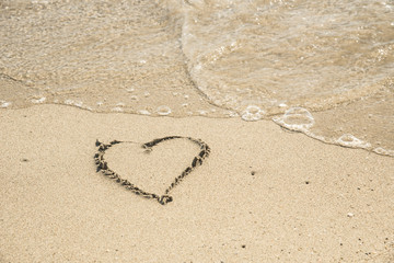 heart on a sand of beach with wave on background