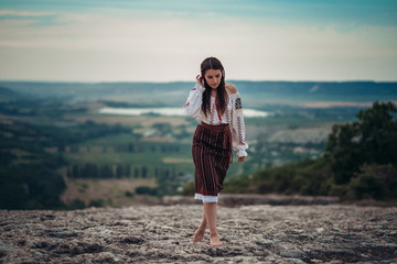 Atractive woman in traditional romanian costume on mountain green blurred background. Outdoor...