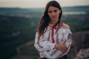 Atractive woman in traditional romanian costume on mountain green blurred background. Outdoor...