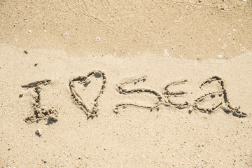 The inscription on the sand near the sea and the waves - I love sea. Background.