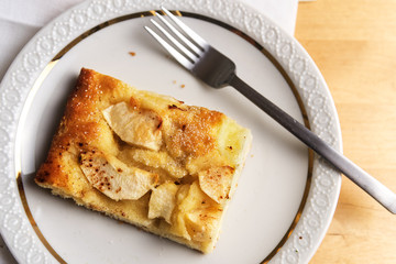 fresh baked apple cake on a white plate on a bright wooden table, overhead view from above, copy space