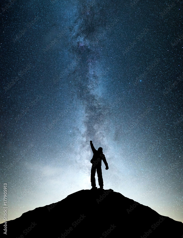 Wall mural Silhouettes of winner on mountain peak. Sport and active life concept on the night sky background.