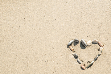 Fototapeta na wymiar Heart shape made of different shells on sand
