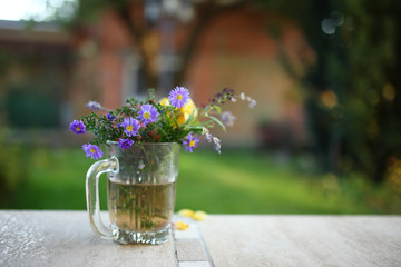 Bouquet of field flowers in glass pot, close up.