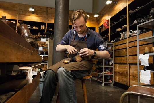 Shoemaker in working in wooden workshop