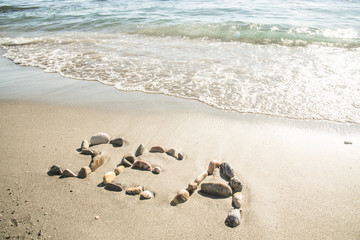 The inscription of the sea with stones on the sand with sea waves