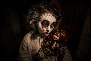 Horror movie scene.Creepy girl with bloody doll in a scary dark room