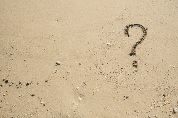 Fototapeta na wymiar Question mark sign on sand beach near the sea and waves