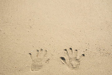 A trace of hands on the wet sand near the sea and waves