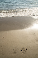 A trace of hands on the wet sand near the sea and waves