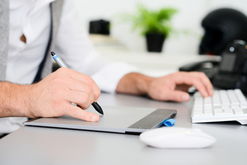 hands detail close-up of male photographer editing photography with a computer and graphic tablet