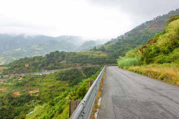 View from road to beauty of Monterosso al Mare, Cinque Terre, Italy. Green mountains and parked cars.