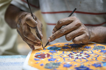 Person drawing traditional tile