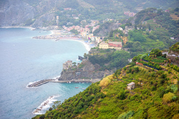 Fototapeta na wymiar Aerial view to the beach of Monterosso al Mare, Cinque Terre, Italy. Houses, parked cars and beautiful green mountains.