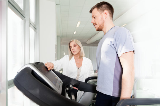 athlete on the treadmill he performs the instructions of physical therapist who assists him