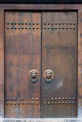 Old brown chinese traditional wooden gate with lion door knockers, China