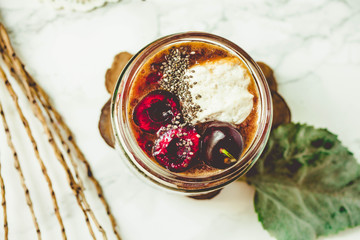 Obraz na płótnie Canvas Chia pudding in a jar with fresh cherries and whipped coconut cream.Detox and healthy superfoods breakfast concept.Top view.Tone and insta size.