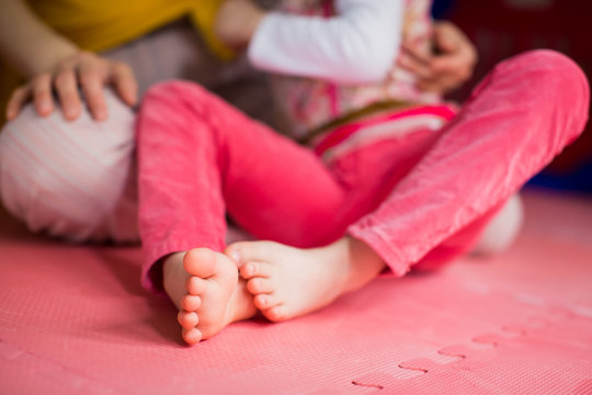 Close-up feet of little disabled girl on the mat indoors