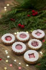 Linzer cookies in a Christmas decoration on a wooden surface.