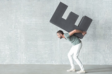 Cheerful cute guy is holding large symbol