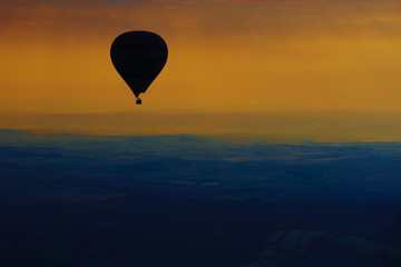 Aerial view of summer countryside during sunset with silhouette of hot air balloon