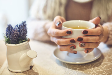 womans hands with cup of tea. woman holding cups of tea. couple on date drinking tea in cafe