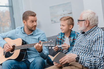 Young father playing guitar with family