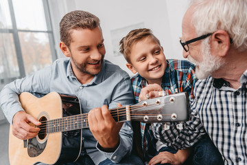 Man playing guitar with family at home