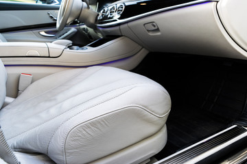 White leather interior of the luxury modern car. Leather comfortable white seats and multimedia. Steering wheel and dashboard. Automatic gear shift. Car interior details.