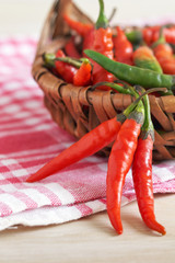 Red chili peppers in woven basket on kitchen table