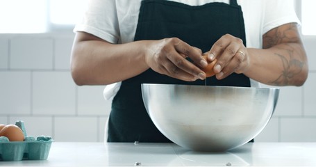 mixed race baker makes a cake. smash eggs