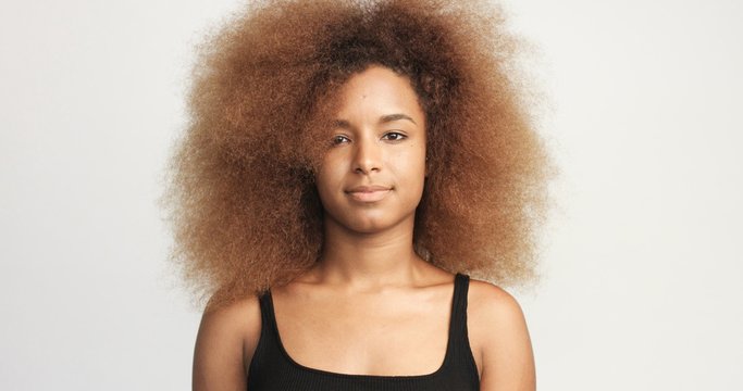 mixed race black woman with blonde curly hair in studio happy smiling