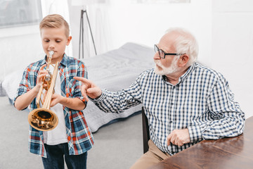 Boy practicing trumpet with grandpa