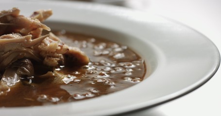 Delicious freshly made hot steaming chicken and lentil soup in a white wide-rimmed plate