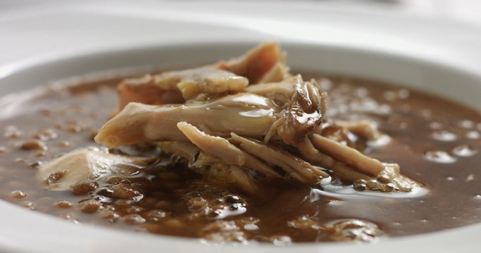 Delicious freshly made hot steaming chicken and lentil soup in a white wide-rimmed plate