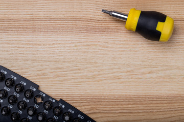 Top view screwdriver with box of bits on wooden table