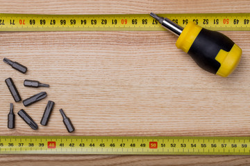 Top view screwdriver with measurement tape on wooden table