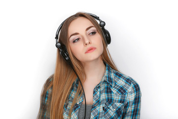 Headshot of a young adorable blonde woman in blue plaid shirt listening to big professional dj headphones.