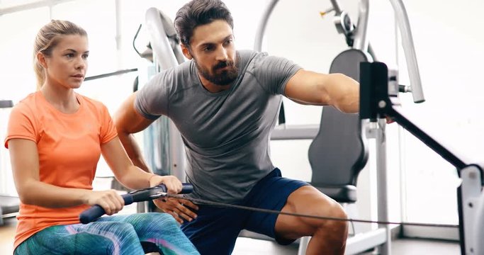 Young beautiful woman doing exercises with personal trainer