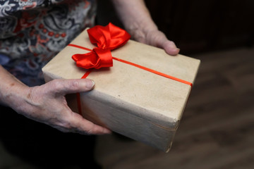 gift box with red bow in grandmother hands