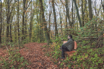 Fototapeta premium Man sitting on wooden bench in forest