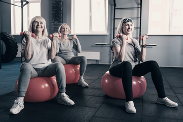 Obraz premium Elderly women working out with dumbbells on exercise balls