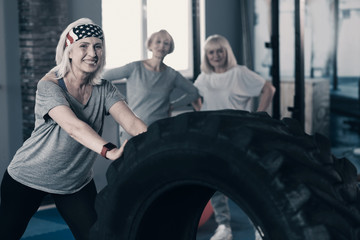 Fototapeta na wymiar Upbeat woman working out with tire in gym